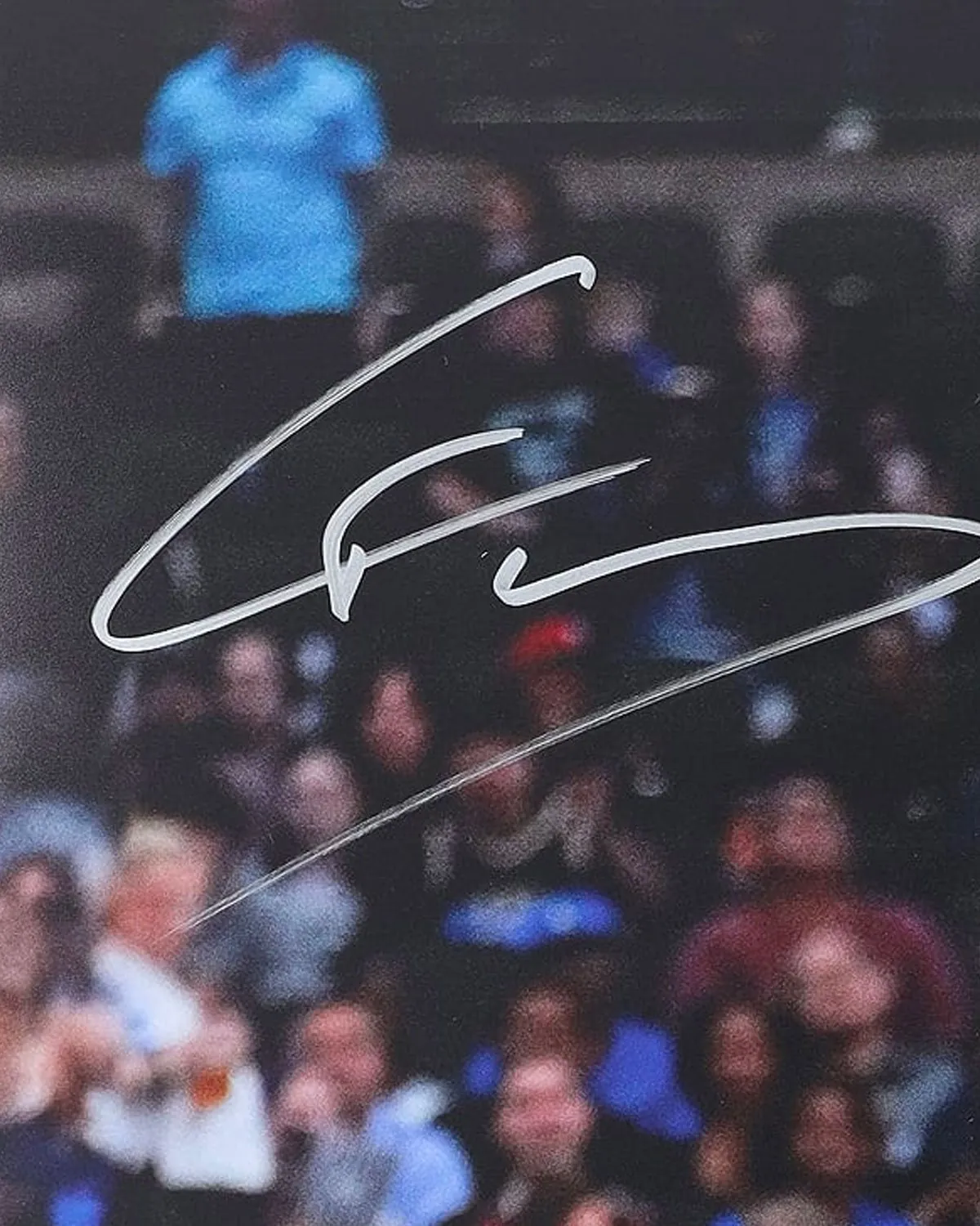 Close-up of an athlete’s signature in silver marker across the photograph